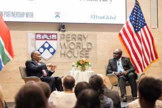 Kgalema Motlanthe and Wale Adebanwi sitting across each other at a table on the stage within the World Forum at Perry World House.